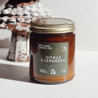 Jar of Citrus Evergreen candle from Red Rock Candle Co. with a decorative tree in the background.